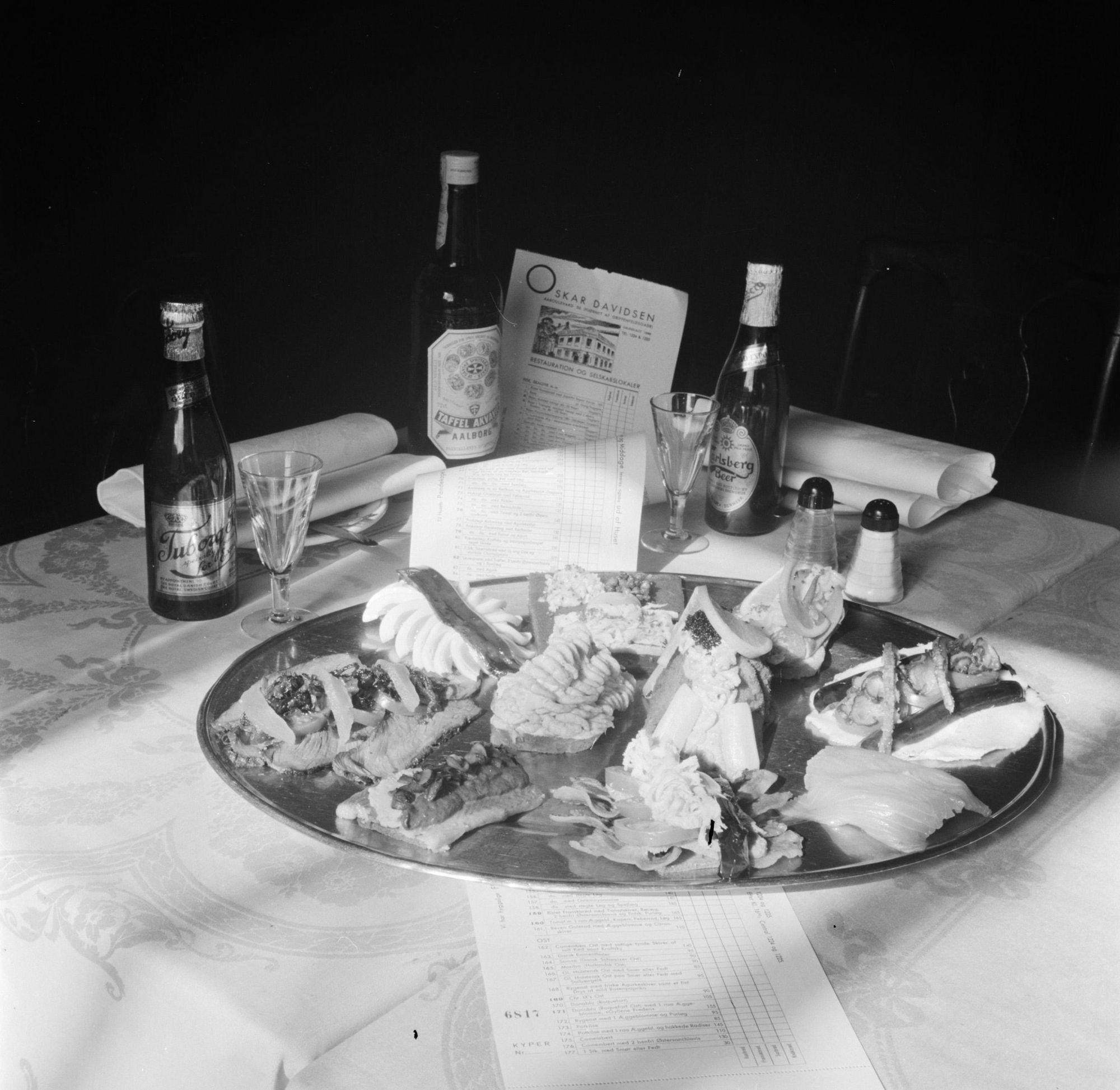 A 1954 photo of various types of smørrebrød, Danish beers, and Aa bottle of Aalborg Taffel Akvavit on it. Photo: Nationaal Archief